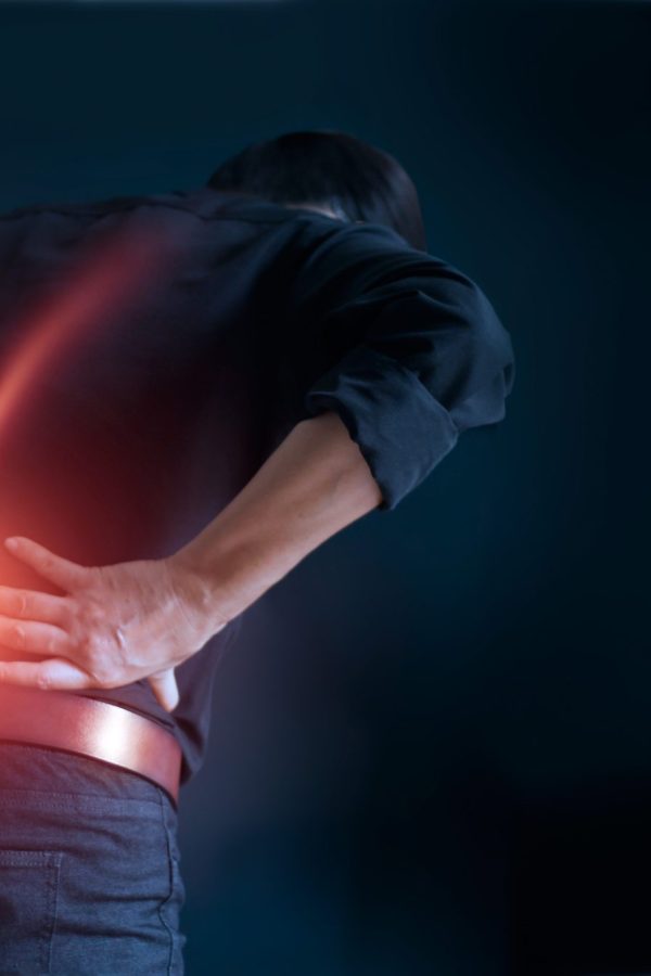 Man suffering from back pain cause of office syndrome, his hands touching on lower back. Medical and heathcare concept